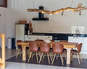 Stylish dining room in Cottage in De Cocksdorp, Texel, with wooden table and modern kitchen.