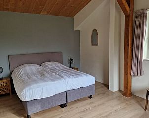 Rustic bedroom in cottage in De Cocksdorp, Texel, with wooden details and serene feel.