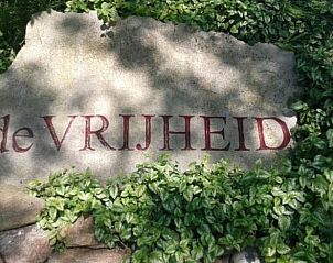 Welcome stone at cottage in De Cocksdorp, Texel, with inscription 'de VRIJHEID' surrounded by greenery.