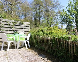 Sonnige Terrasse des Ferienhauses Kikkertstraat 60, De Cocksdorp, Texel mit Gartentisch und grner Umgebung.