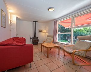 Gemtliches Wohnzimmer des Ferienhauses Slufterduin 088, Texel, mit bequemen Sitzgelegenheiten und Blick auf den Garten.