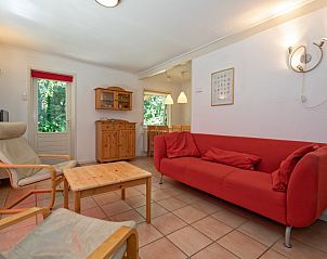 Innenbereich des Ferienhauses Slufterduin 088 in De Cocksdorp, Texel, mit rotem Sofa und Essecke.