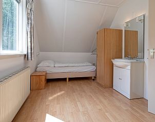Helles Schlafzimmer mit Einzelbett im Ferienhaus Slufterduin 098, Texel, mit Holzboden und Waschbecken.