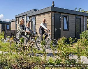 Die Familie radelt am Chalet Typ Vuurtoren de Luxe in De Cocksdorp auf Texel vorbei, umgeben von Natur.