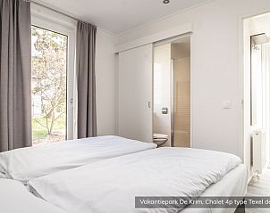 Schlafzimmer im Chalet Typ Texel de Luxe, De Cocksdorp, Texel mit bequemen Betten und Gartenblick.