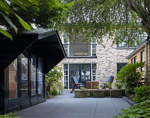 Cozy courtyard of Het Kwade Konijn, vacation home in De Cocksdorp, Texel, with comfortable chairs and green surroundings.