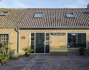 Sunny entrance to Het Kwade Konijn, vacation home in De Cocksdorp, Texel, with inviting bench and flower pots.