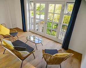 Bright sitting area on the top floor of Het Kwade Konijn, vacation home in De Cocksdorp, Texel, overlooking green surroundings.