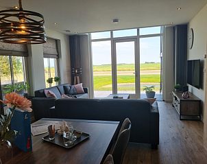 Bright living room of vacation home Eierland in De Cocksdorp, Texel, with large windows and views of nature.