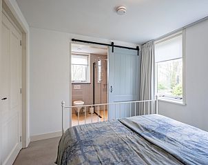 Sfeervolle slaapkamer van Bungalow Postweg 109 in De Cocksdorp, Texel, met ensuite badkamer en uitzicht op de groene omgeving.