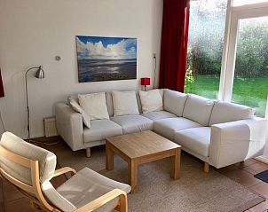 Cozy sitting area in Bungalowpark Slufteroord, De Cocksdorp Texel, with comfortable sofa and view of the green garden.