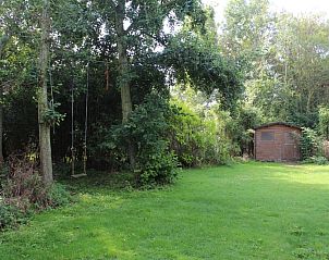 Green garden with swing and gazebo at Holiday home Slufteroord 270, De Cocksdorp Texel, for relaxation and nature experience.