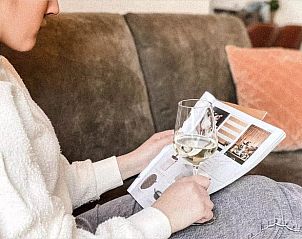 Entspannter Moment im Ferienhaus in De Cocksdorp, Texel, mit einem Glas Wein und einer Zeitschrift auf dem Sofa auf den Watteninseln.