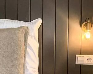 Sfeervolle slaapkamer in Huisje in De Cocksdorp, Texel, met houten lambrisering en zachte verlichting.