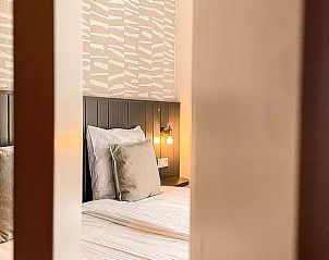 Slaapkamer in Huisje in De Cocksdorp, Texel, met uitzicht op de gang en sfeervolle verlichting.