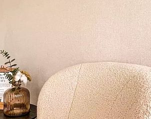 Gezellige zithoek in Huisje in De Cocksdorp, Texel, met comfortabele stoel en decoratieve vaas.