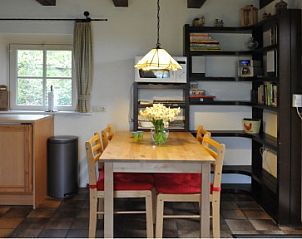 Eethoek met houten tafel in Wind en Zee vakantiehuis, De Koog, Texel, omgeven door boeken.