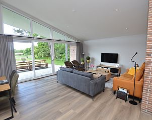 Bright living room of Orchismient 49 vacation home in De Koog, Texel with views of greenery and spacious seating area.