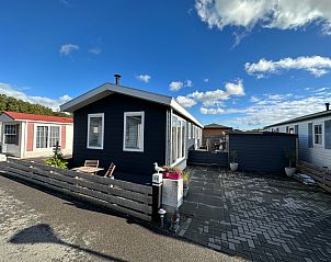 Chalet Bregkoog 52 in De Koog Texel mit groer Auffahrt und blauem Himmel.