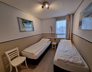 Schlafzimmer mit zwei Betten in Appartements Anna - Zeenevel - 9, De Koog, Texel, mit Stranddekoration an der Wand.