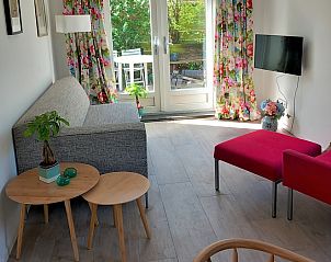 Cozy living room in Huisje Quirijn, De Koog Texel with colorful curtains and French doors to the garden.