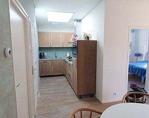 Modern kitchen in vacation home Huisje Quirijn, De Koog Texel with wooden cabinets and light through skylight.