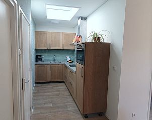 Compact kitchen in Cottage Quirijn, De Koog Texel with sleek wooden finish and modern appliances.