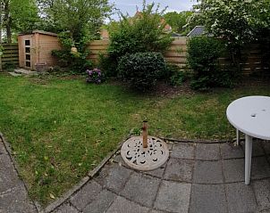 Spacious garden of vacation home Huisje Quirijn, De Koog Texel with terrace and green fence.