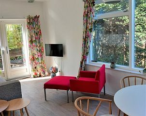 Stylish living space in Huisje Quirijn, De Koog Texel with red armchairs and lots of natural light.