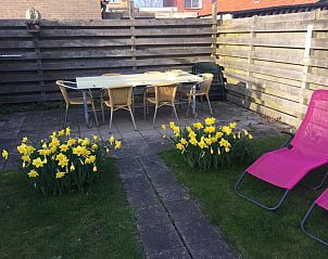 Outdoor terrace of De Duinputter in De Koog Texel with dining table, flowers and deck chairs.
