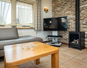 Modern living room in Villa, De Koog, Texel with flat-screen TV and cozy fireplace.