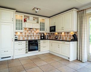 Spacious kitchen in Villa, De Koog, Texel with classic white cabinets and access to the garden.