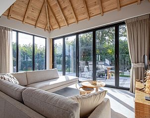 Bright living room of Villa Flo, Texel with large windows and views of the garden.