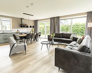 Stylish living room of Villa 17 in De Koog, Texel with open kitchen and garden view for a comfortable stay.