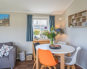Dining area Chalet Bregkoog 227, Chaletpark Bregkoog, De Koog, Texel with modern chairs and decorative flowers.