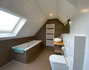 Modern bathroom in Villapark Kamperfoelie - Holiday home Kamperfoelie 53, De Koog, Texel with bathtub and skylight.