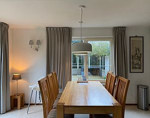 Dining room with wooden table in Villapark Kamperfoelie - Holiday home Kamperfoelie 53, De Koog, Texel overlooking the garden.