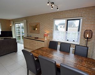 Dining room in Holiday home Stappeland 213, De Koog, Texel with wooden table and lots of light through large windows.