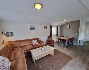 Cozy living room in Chaletpark Bregkoog - Chalet Bregkoog 235, De Koog, Texel with comfortable sitting area and dining area.