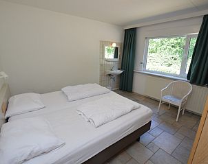 Comfortable bedroom with large window in Epelaan 31, vacation home in De Koog, Texel, overlooking nature.