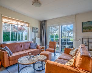 Cozy living room in Maaikeduinweg 13 vacation home, De Koog, Texel with comfortable seating area and garden view.