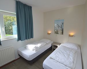 Second bedroom in Orchismient 27, De Koog, Texel, with two single beds and garden view.