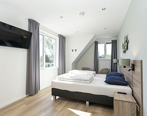 Corner room in Villa 37a, De Koog, Texel, vacation home with large bed and view of green surroundings.