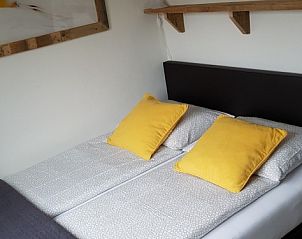 Gemtliches Schlafzimmer im Ferienhaus 1, De Koog, Texel mit Doppelbett und bunten Kissen.