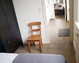 Schlafzimmer im Ferienhaus 1, De Koog, Texel mit Blick auf den Korridor und rustikalem Stuhl.
