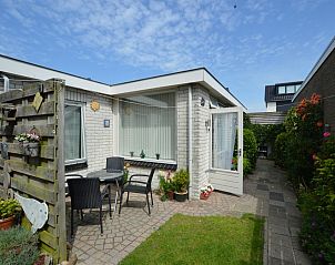 Cozy terrace at Plevierstraat 18 vacation home in De Koog, Texel with outdoor seating and flowering garden.