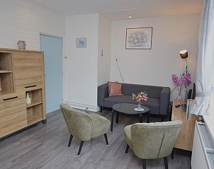 Modern living room in vacation home Plevierstraat 18, De Koog, Texel with comfortable seating area and wooden cupboard.