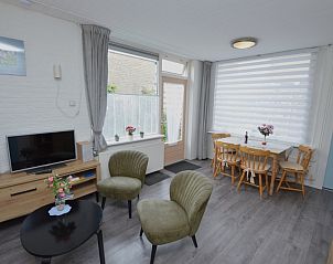 Bright dining and living room in vacation home Plevierstraat 18, De Koog, Texel with dining table and television.