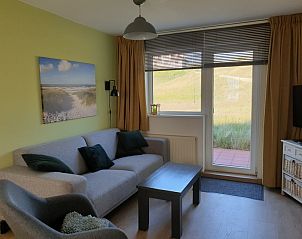 Sunny sitting area in De Duinpan - Duinhuisje Texel, De Koog, overlooking the dunes through large windows.