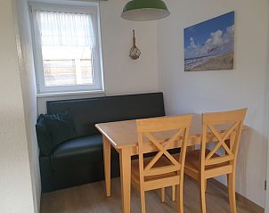 Dining area in De Duinpan - Duinhuisje Texel, De Koog, with wooden table and cozy sofa for family meals.